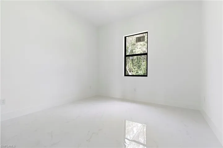 Unfurnished room featuring light marble finish flooring and baseboards