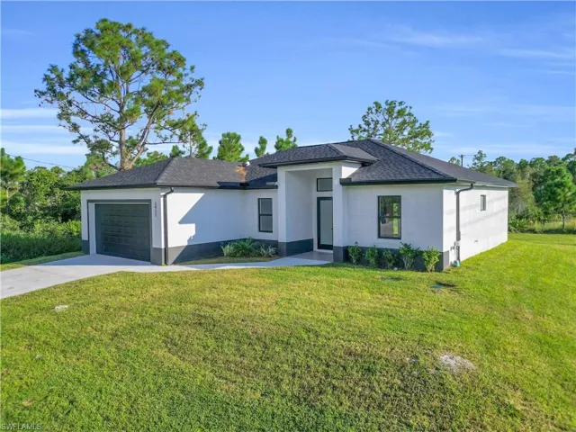 Prairie-style home featuring driveway, a front lawn, a garage, stucco siding, and a shingled roof