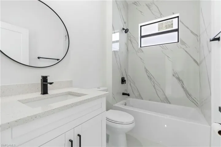 Bathroom with shower / tub combination, vanity, and marble finish flooring