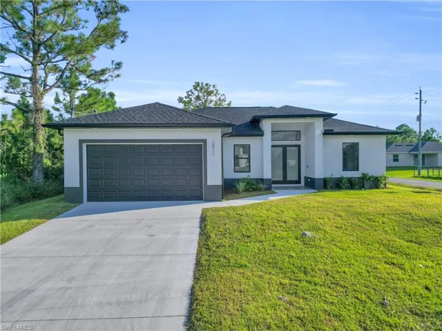 Prairie-style house featuring stucco siding, driveway, a front yard, and a garage