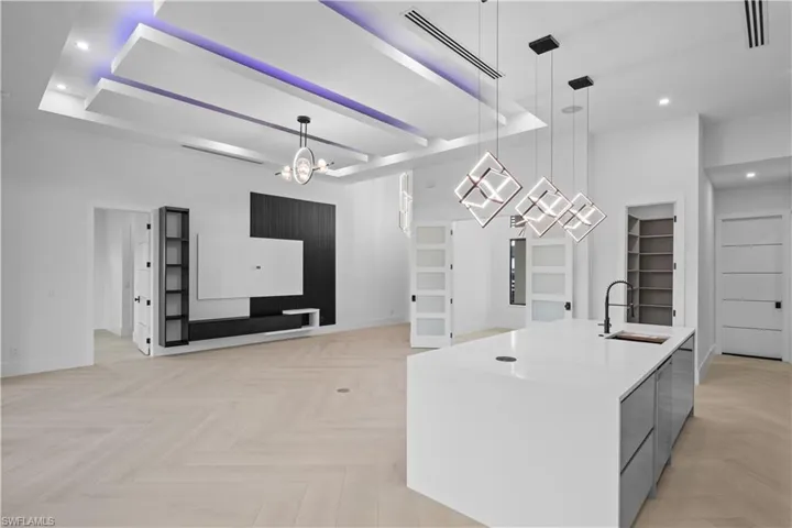 Kitchen featuring recessed lighting, modern cabinets, pendant lighting, light countertops, and a chandelier