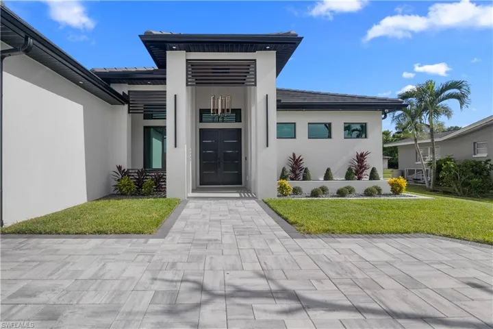 View of exterior entry featuring stucco siding and a yard