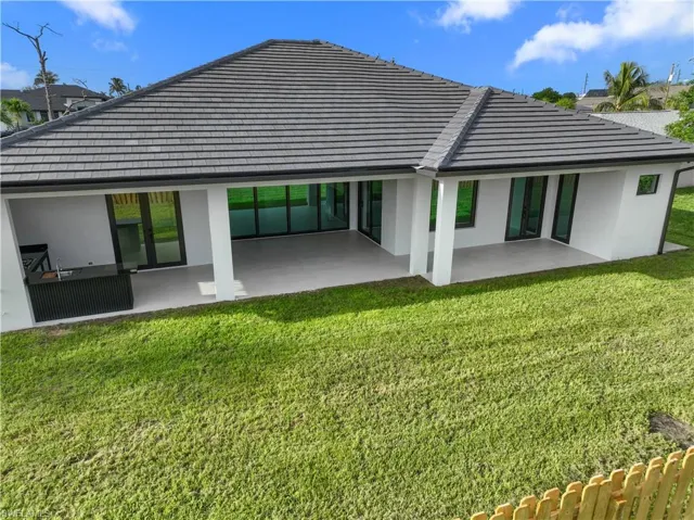 Rear view of property featuring stucco siding, a patio, a lawn, and a tiled roof