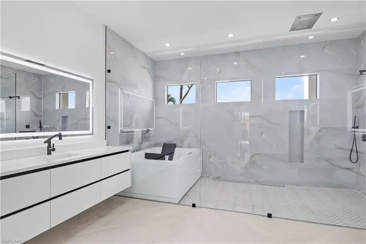 Full bathroom with vanity, a bath, a marble finish shower, and recessed lighting
