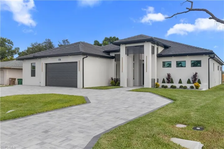 Prairie-style home with an attached garage, decorative driveway, a front yard, and a tile roof
