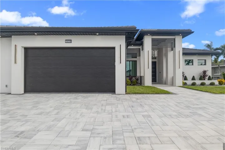 Modern home featuring stucco siding, an attached garage, and driveway