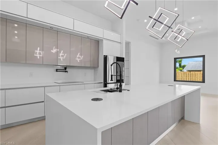 Kitchen with modern cabinets, white cabinetry, a large island with sink, recessed lighting, and light countertops