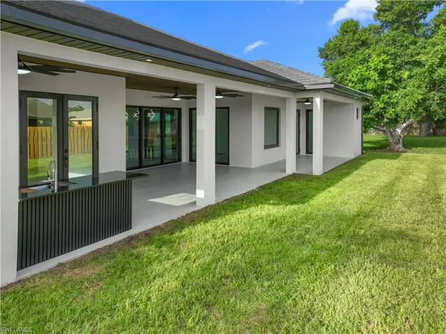 Rear view of property with a ceiling fan, stucco siding, a lawn, and a patio area