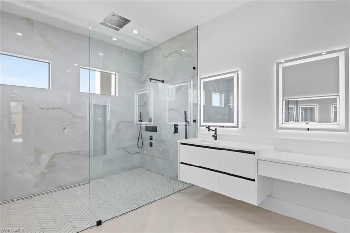 Bathroom with vanity and a marble finish shower