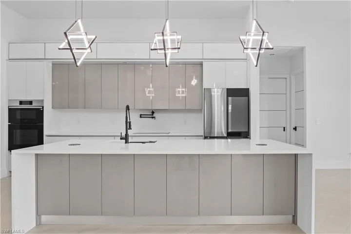 Kitchen featuring modern cabinets, white cabinetry, refrigerator, a large island, and light countertops