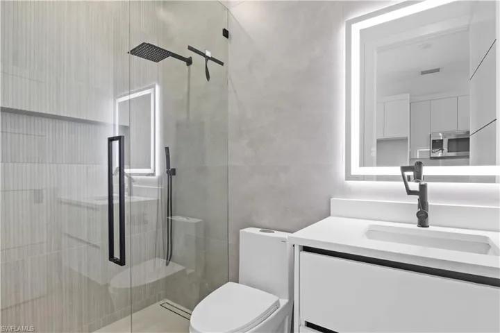 Bathroom featuring vanity, a shower stall, and tile walls