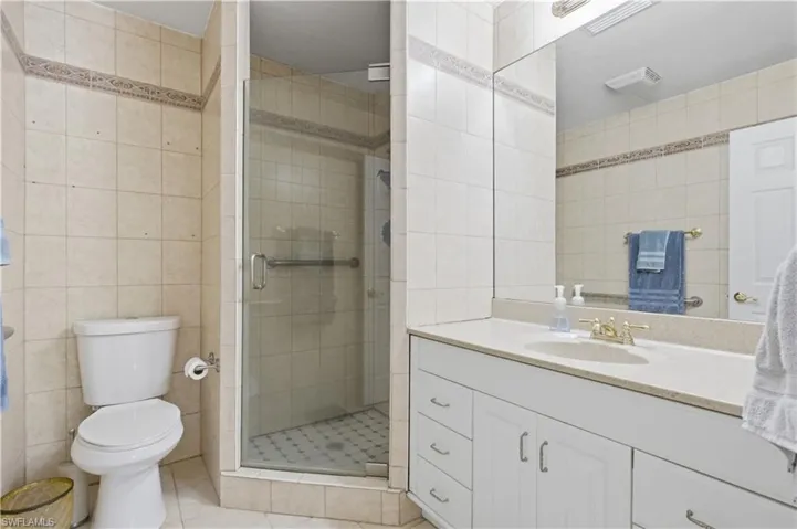 Bathroom featuring a glass-enclosed shower, white vanity with integrated sink, light-toned countertop, and full-width wall mirror