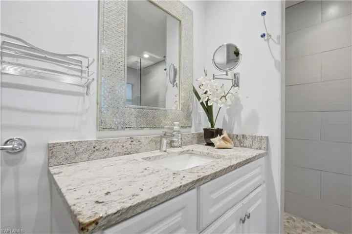 Bathroom vanity featuring a speckled countertop, integrated sink, and white cabinetry