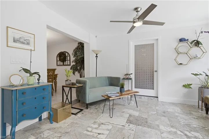 Spacious living area featuring light-toned tile flooring, recessed lighting, and a contemporary ceiling fan
