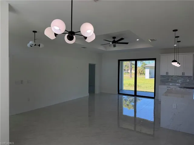 Unfurnished room featuring a tray ceiling, a chandelier, recessed lighting, and a ceiling fan