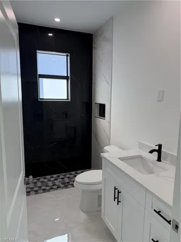 Full bathroom with vanity, a marble finish shower, and recessed lighting