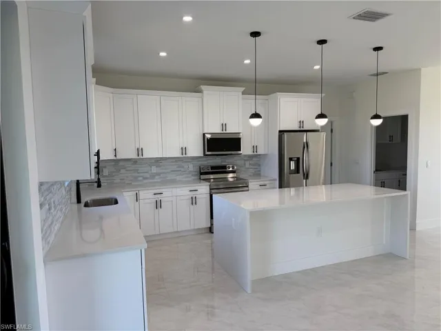 Kitchen with tasteful backsplash, stainless steel appliances, light stone countertops, white cabinetry, and recessed lighting