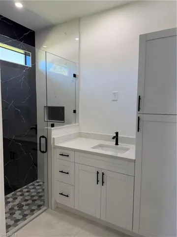 Full bath with vanity and a marble finish shower