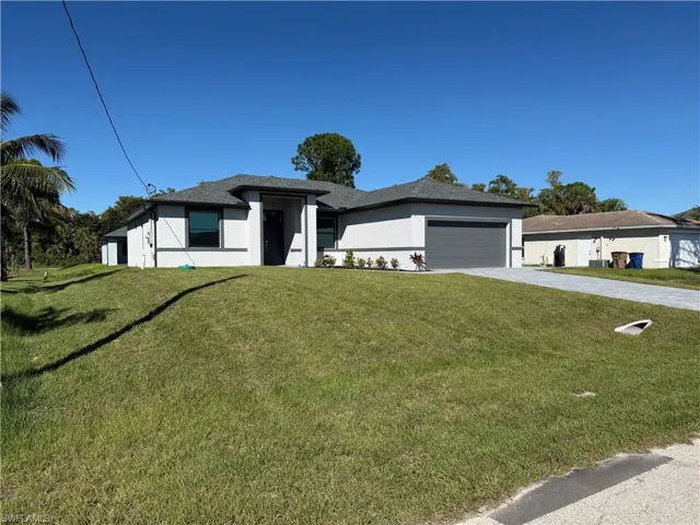 Prairie-style house with stucco siding, a front yard, decorative driveway, and a garage