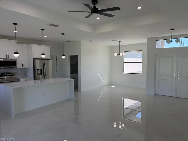 Kitchen featuring a raised ceiling, appliances with stainless steel finishes, decorative light fixtures, and recessed lighting