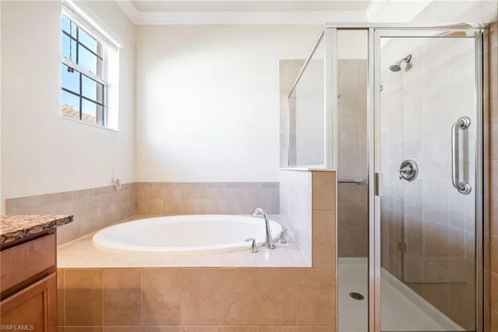 Bathroom featuring ornamental molding, separate shower and tub, and vanity