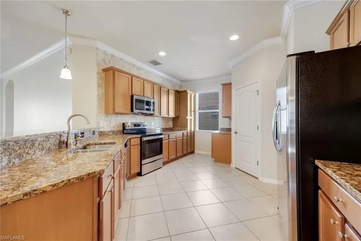 Kitchen featuring pendant lighting, ornamental molding, stainless steel appliances, and sink