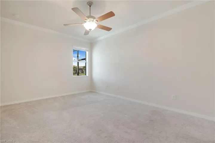 Carpeted spare room with crown molding and ceiling fan