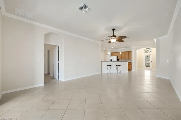 Unfurnished living room with crown molding, light tile patterned floors, and ceiling fan