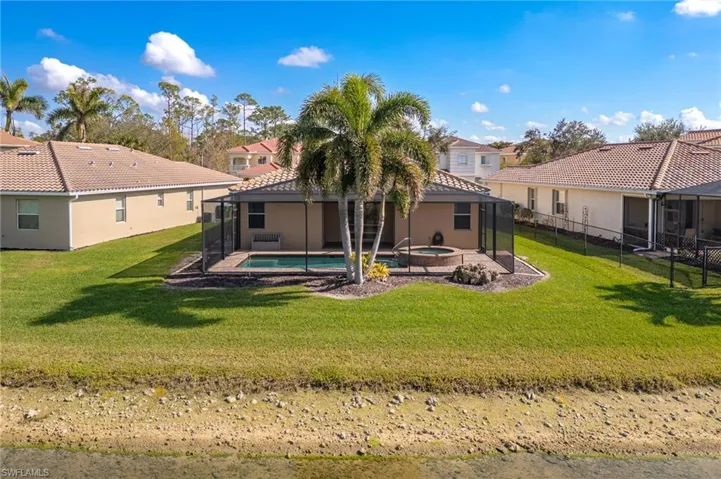 Back of property featuring a swimming pool with hot tub, a lanai, and a lawn