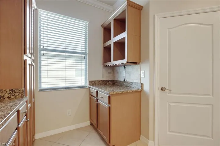 Kitchen featuring light tile patterned floors, backsplash, ornamental molding, and a healthy amount of sunlight
