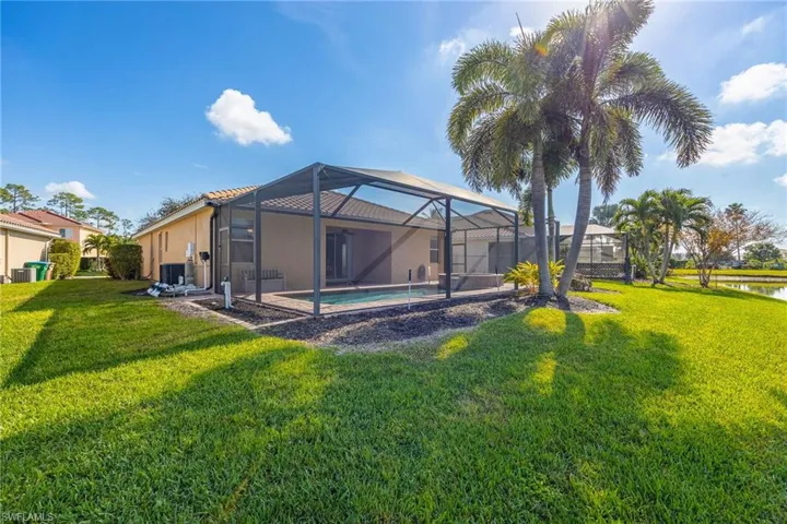 Back of house featuring a lanai, a lawn, central AC, and a water view