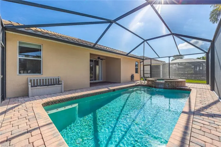 View of swimming pool featuring ceiling fan, a patio, glass enclosure, and an in ground hot tub