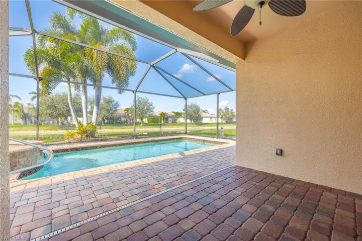 View of swimming pool featuring a patio, ceiling fan, and glass enclosure