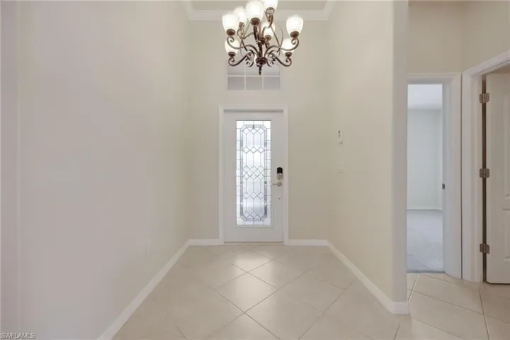 Foyer entrance featuring light tile patterned floors, a notable chandelier, and ornamental molding
