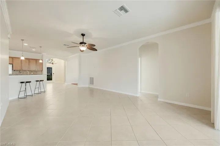 Unfurnished living room with crown molding, ceiling fan, and light tile patterned flooring