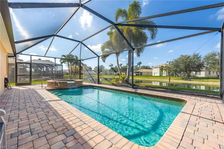 View of pool with a water view, an in ground hot tub, a lanai, and a patio area