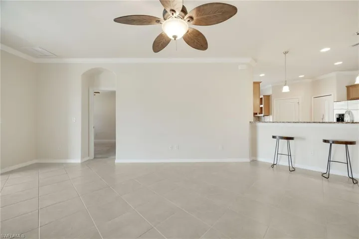 Unfurnished living room featuring light tile patterned floors, crown molding, and ceiling fan
