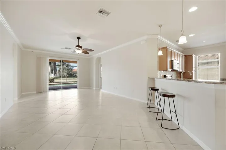 Kitchen with tasteful backsplash, light tile patterned flooring, ornamental molding, and kitchen peninsula