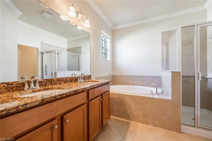 Bathroom featuring crown molding, vanity, tile patterned floors, and plus walk in shower