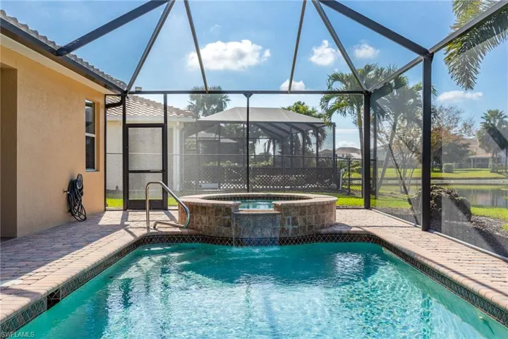 View of pool with an in ground hot tub, a patio, and glass enclosure