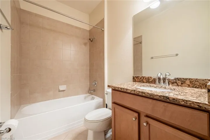 Full bathroom with tiled shower / bath combo, vanity, tile patterned flooring, and toilet