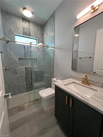 Bathroom with vanity and a marble finish shower