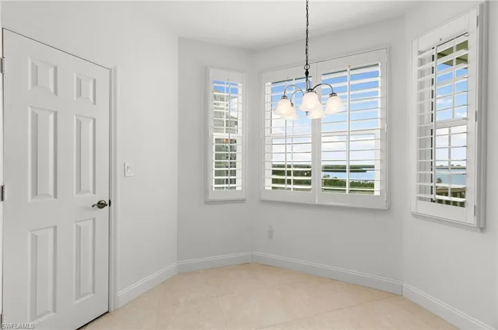 Tiled spare room featuring an inviting chandelier