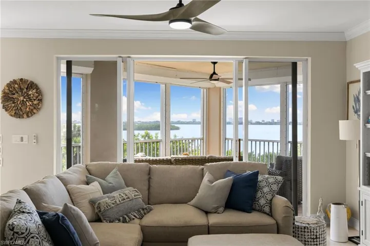 Living room featuring ceiling fan, a water view, and ornamental molding