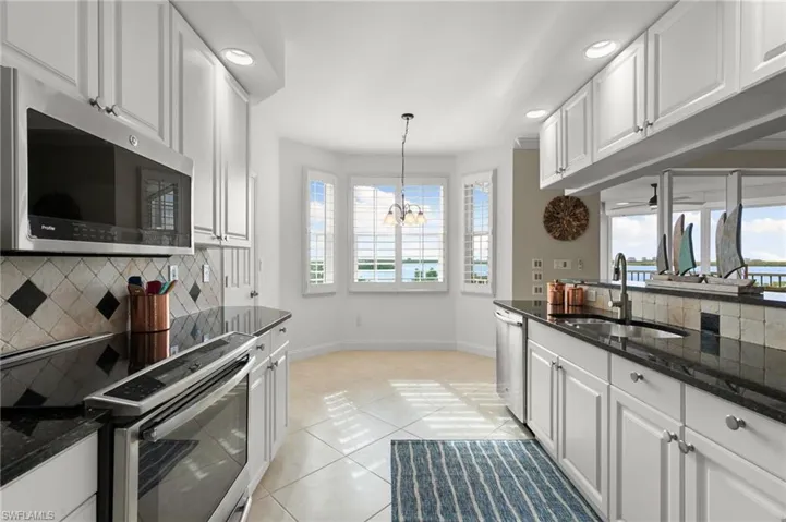 Kitchen with white cabinets, light tile patterned flooring, and appliances with stainless steel finishes