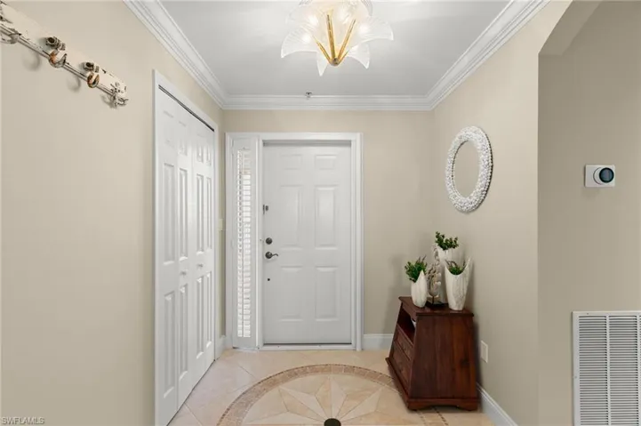 Foyer entrance featuring ornamental molding and light tile patterned floors