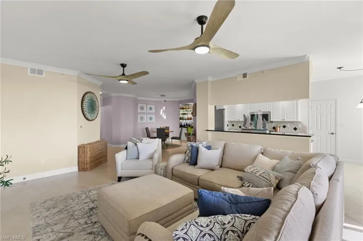 Living room featuring crown molding, light tile patterned floors, and ceiling fan