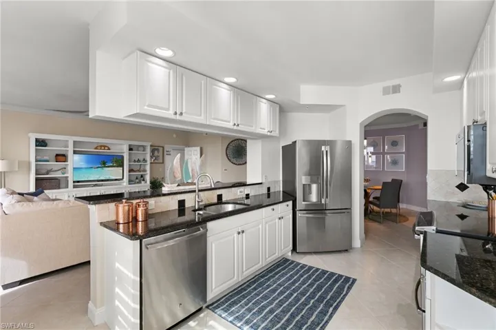 Kitchen with white cabinets, sink, appliances with stainless steel finishes, kitchen peninsula, and backsplash