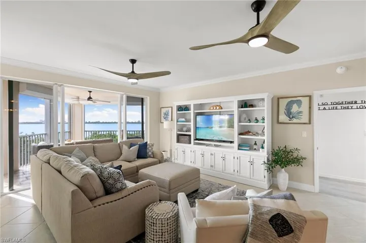 Living room with ceiling fan, crown molding, and light tile patterned floors