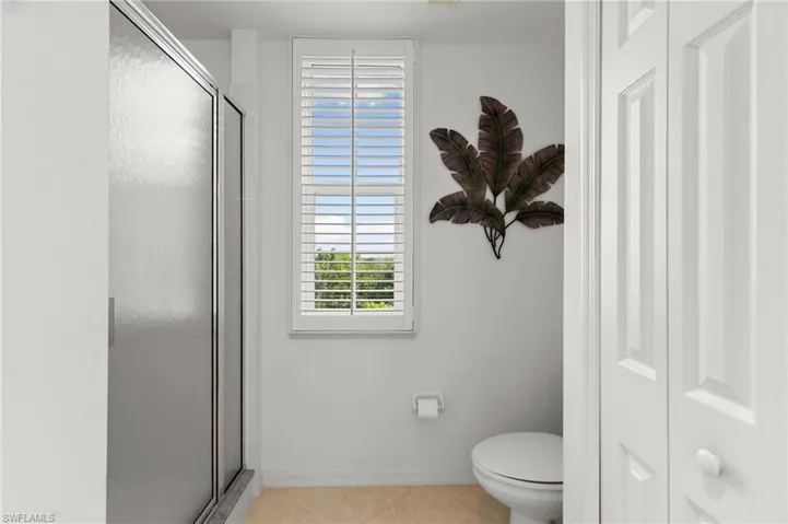 Bathroom featuring toilet, tile patterned flooring, and a shower with door
